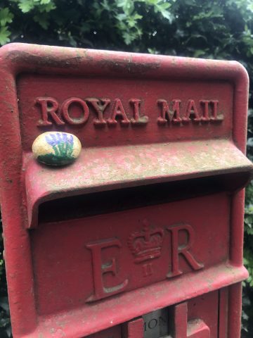 lavender painted on a rock, hidden on a post box