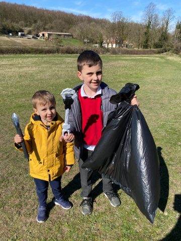 two boys collecting litter with a black sack