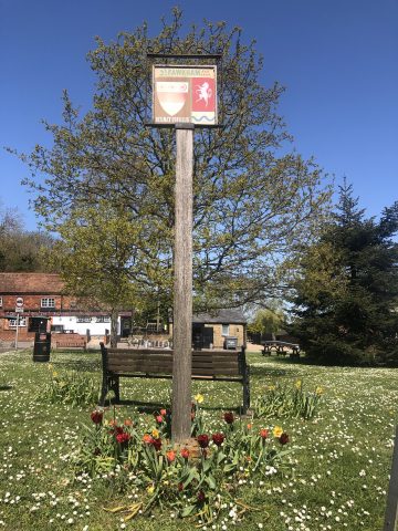 Fawkham sign on wooden post with tulips in flower beneath it