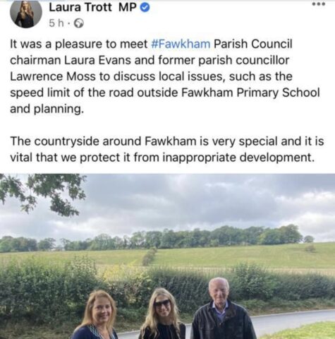 three people including local MP standing in front of fields 